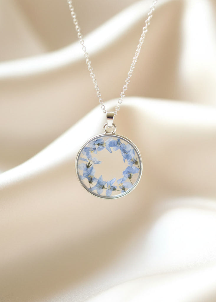 Necklace with a round pendant featuring dried flowers on a beige background