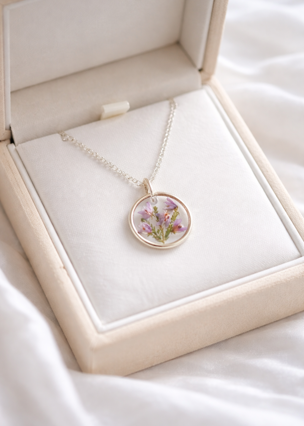 Necklace with a floral pendant in an open jewelry box on a white fabric background
