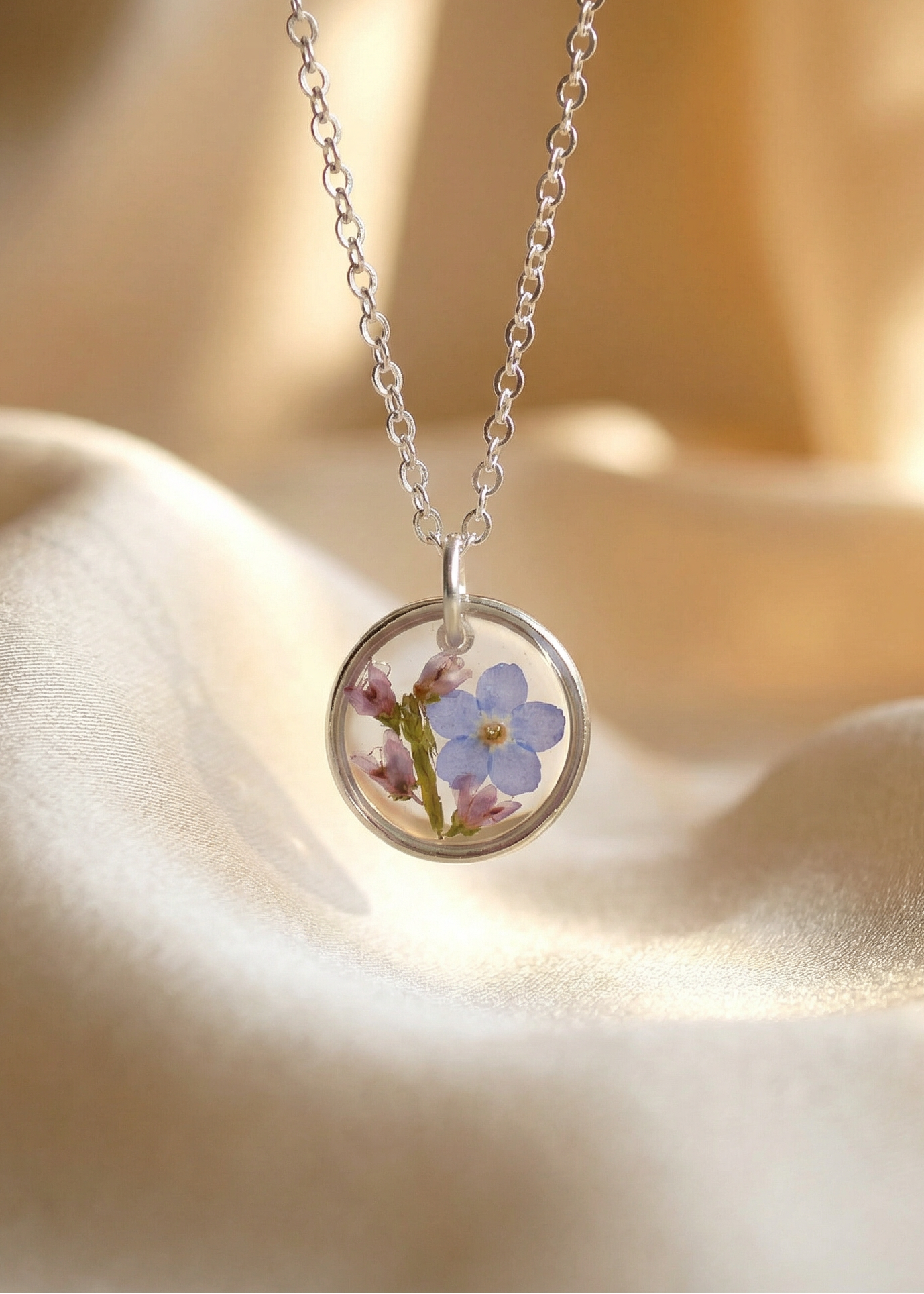 Silver necklace with a round pendant featuring a pressed flower on a soft beige background