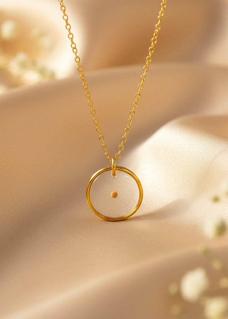 Gold necklace with a circular pendant on a soft beige background
